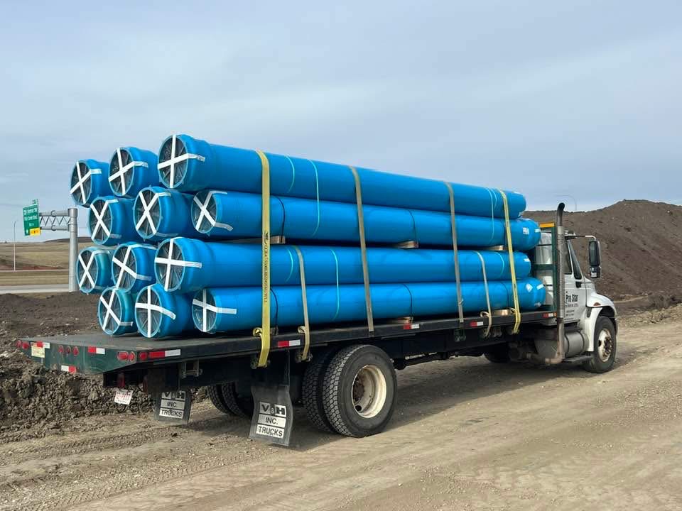 Large blue industrial pipes loaded on commercial flatbed truck
